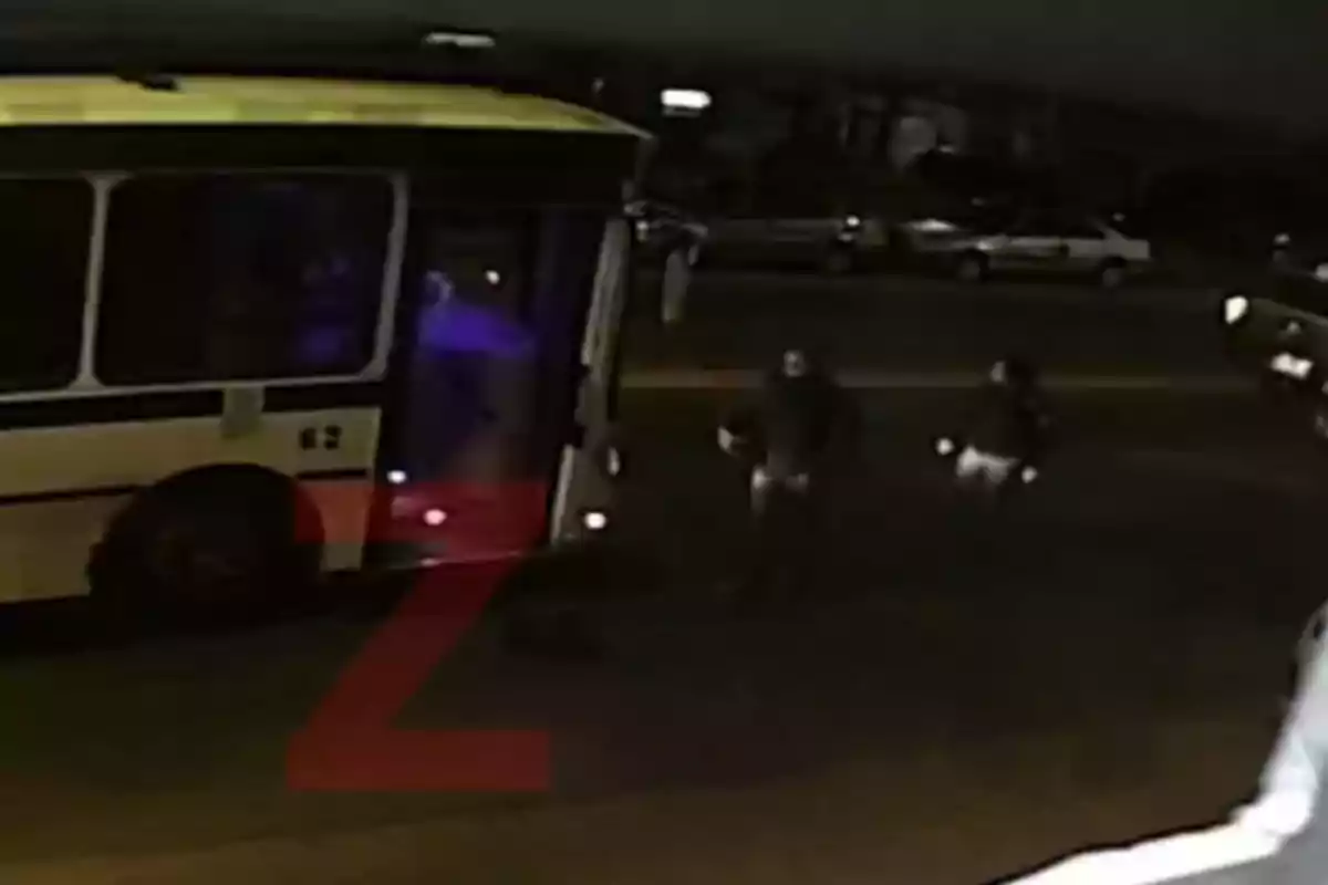Two people walking toward the open door of a bus on a street at night Two people walking toward the open door of a bus on a street at night