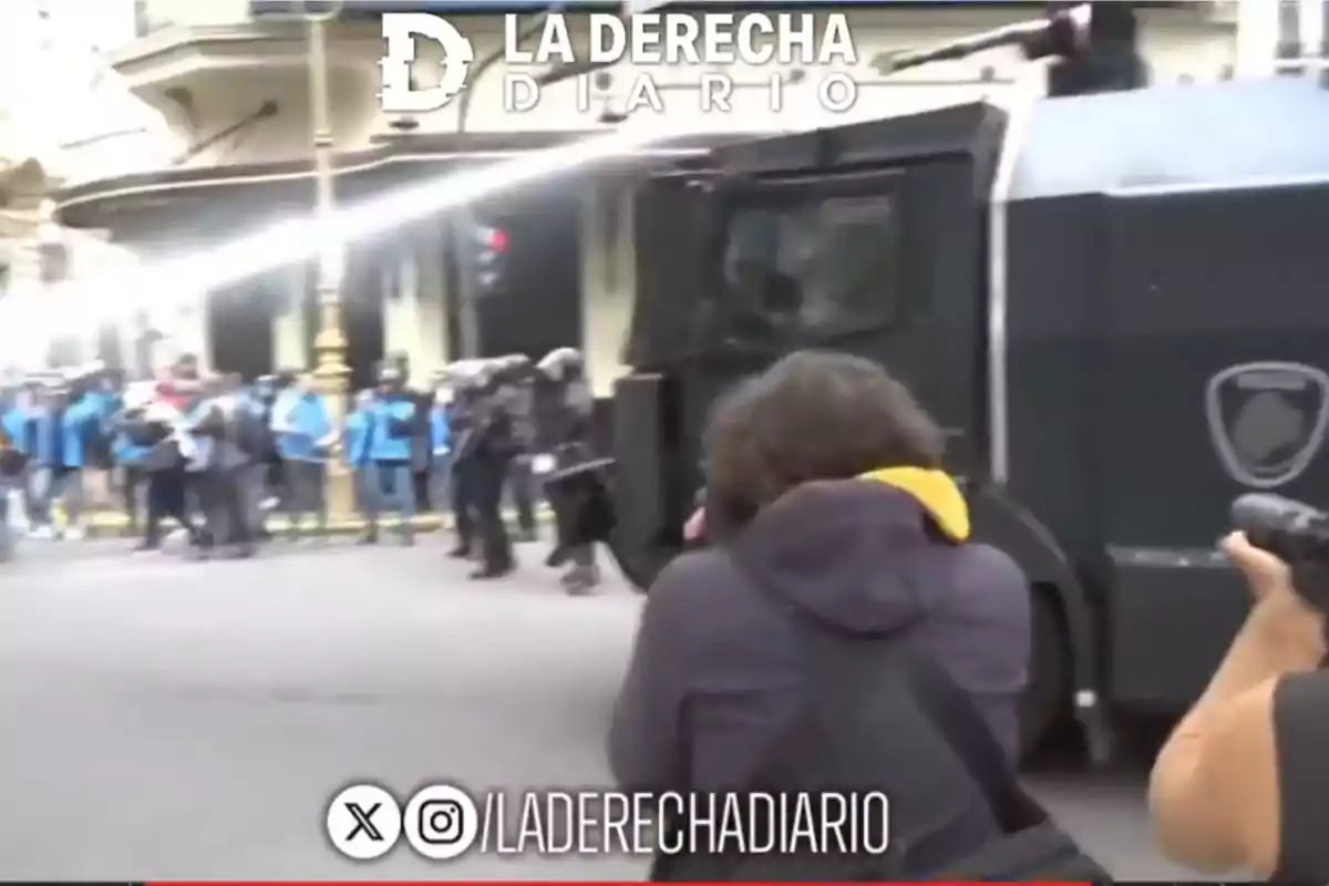 Photographers capture the moment when a police water cannon truck disperses protesters on an urban street while a group of officers watches in the background. Photographers capture the moment when a police water cannon truck disperses protesters on an urban street while a group of officers watches in the background.