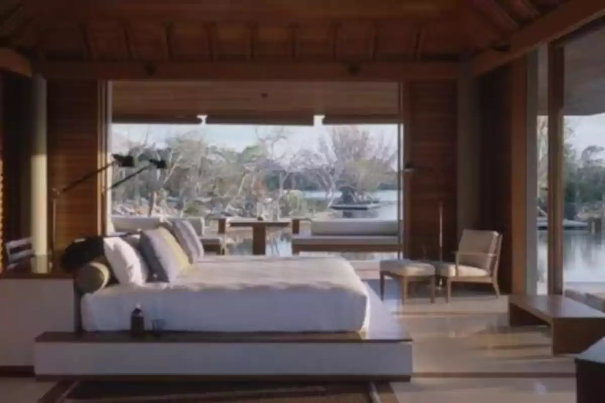 Habitación moderna con cama grande, ventanales de madera y vista a un lago rodeado de árboles
