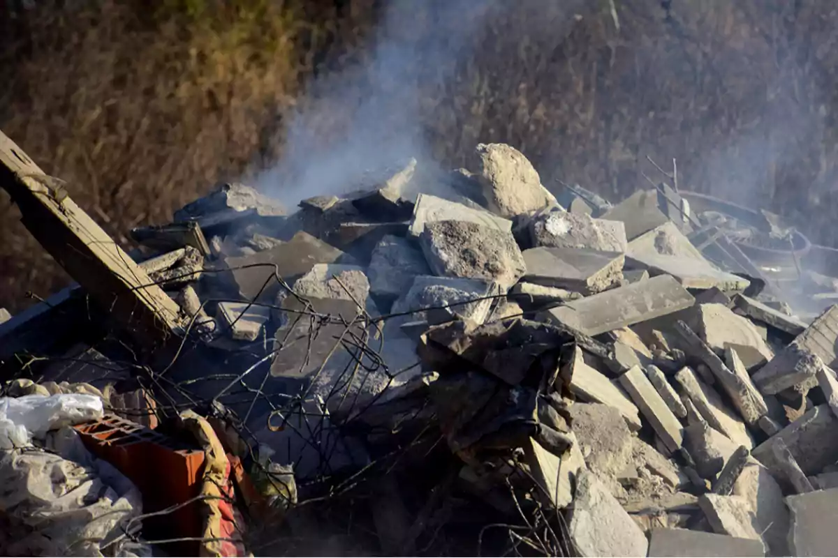 Pile of construction debris with cement blocks, rebar, and smoke rising from the rubble Pile of construction debris with cement blocks, rebar, and smoke rising from the rubble