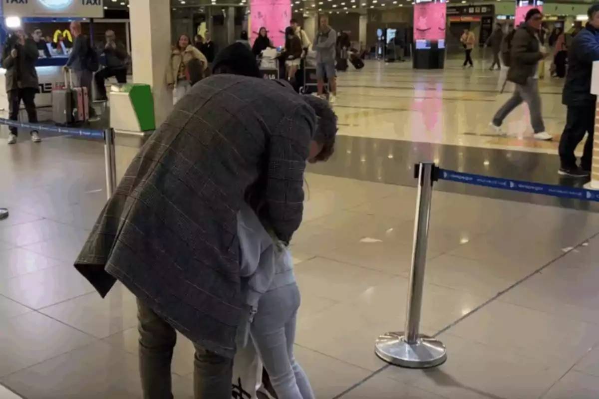 A man hugging a girl at an airport while other people walk around. A man hugging a girl at an airport while other people walk around.