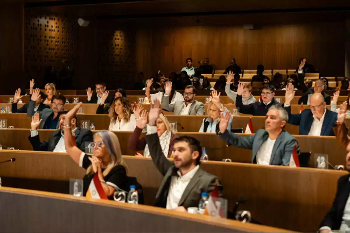 Personas en una sala de reuniones levantando la mano durante una votación
