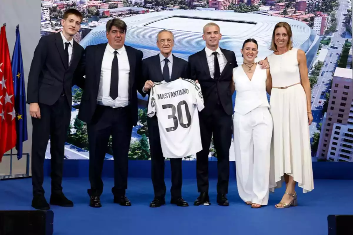 Group of elegantly dressed people posing together while one of them holds a soccer jersey with the name Mastantuono and the number 30 in front of an image of a stadium Group of elegantly dressed people posing together while one of them holds a soccer jersey with the name Mastantuono and the number 30 in front of an image of a stadium