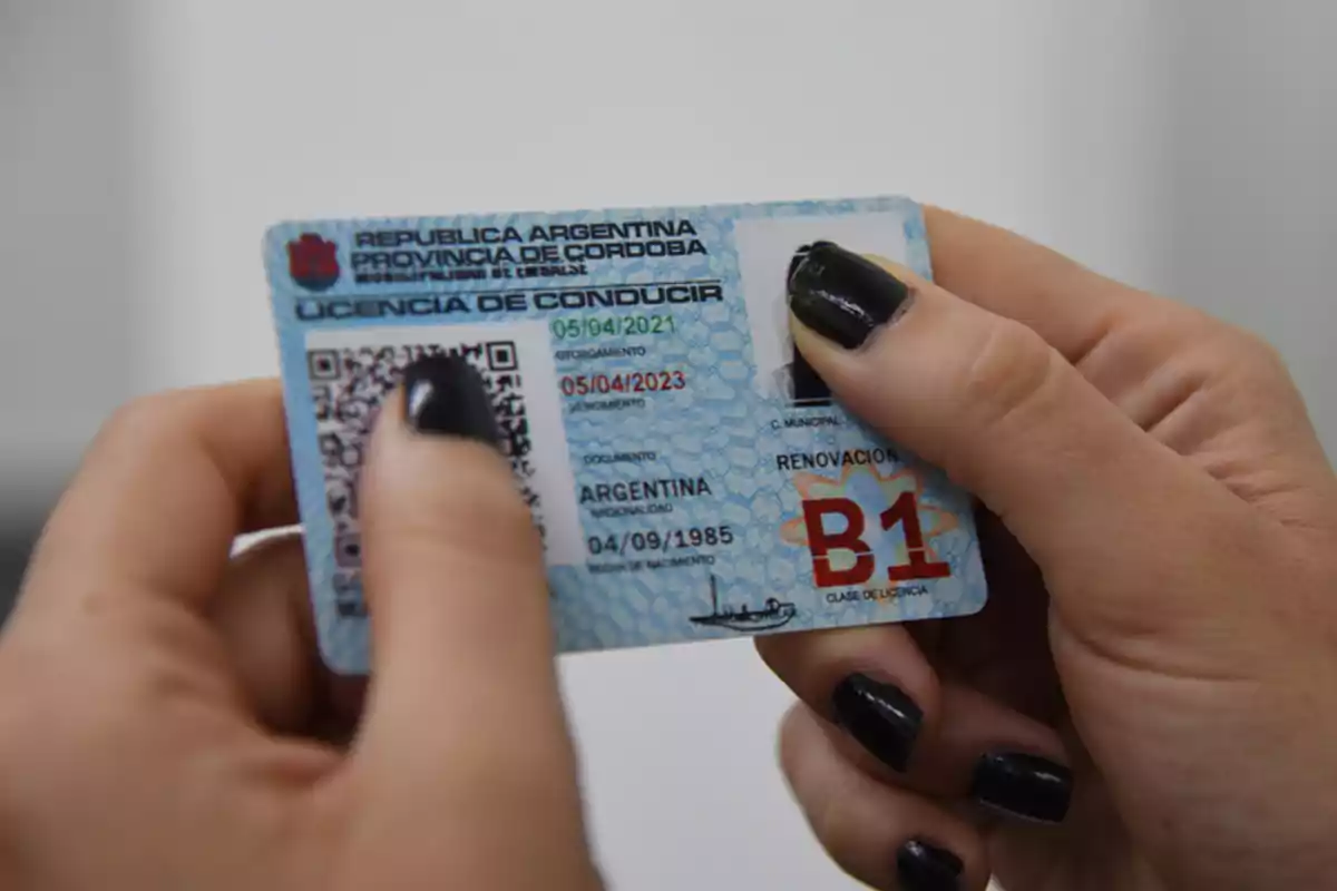 Persona sosteniendo una licencia de conducir argentina de la provincia de Córdoba con las uñas pintadas de negro