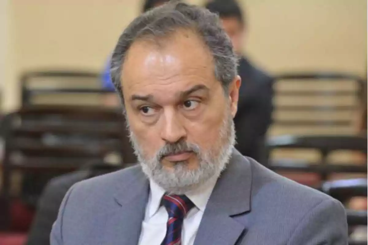Gray-haired, bearded man in a suit and tie sitting in a public place looking to the side Gray-haired, bearded man in a suit and tie sitting in a public place looking to the side