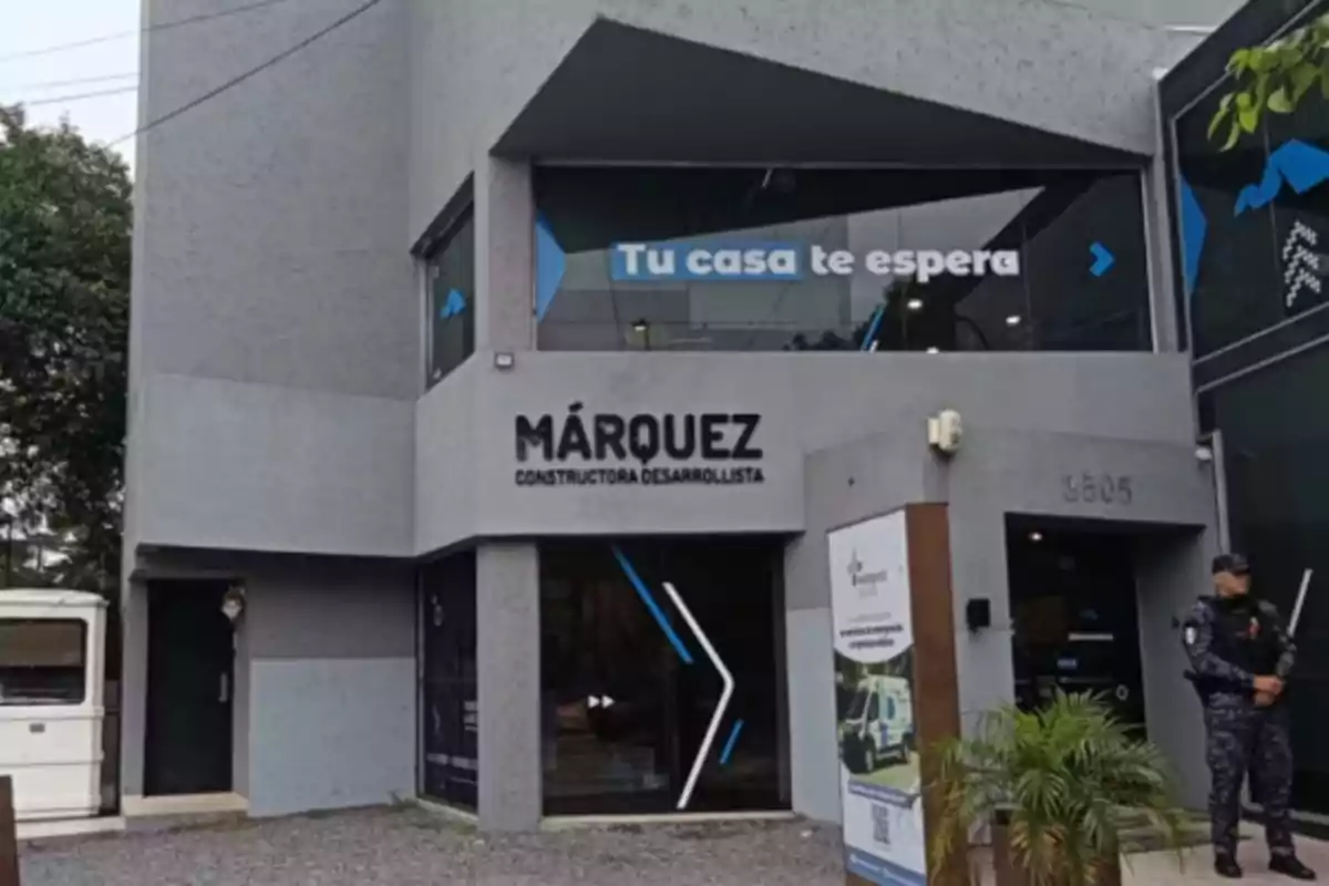 Facade of a construction company called Márquez with a sign that says "Your home is waiting for you" and a security guard at the entrance