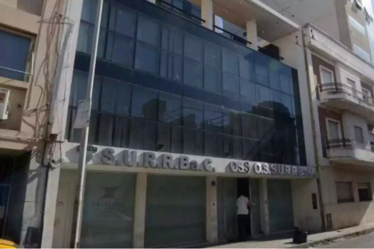 Facade of a modern building with large glass windows and a sign at the entrance that says SURRBaC