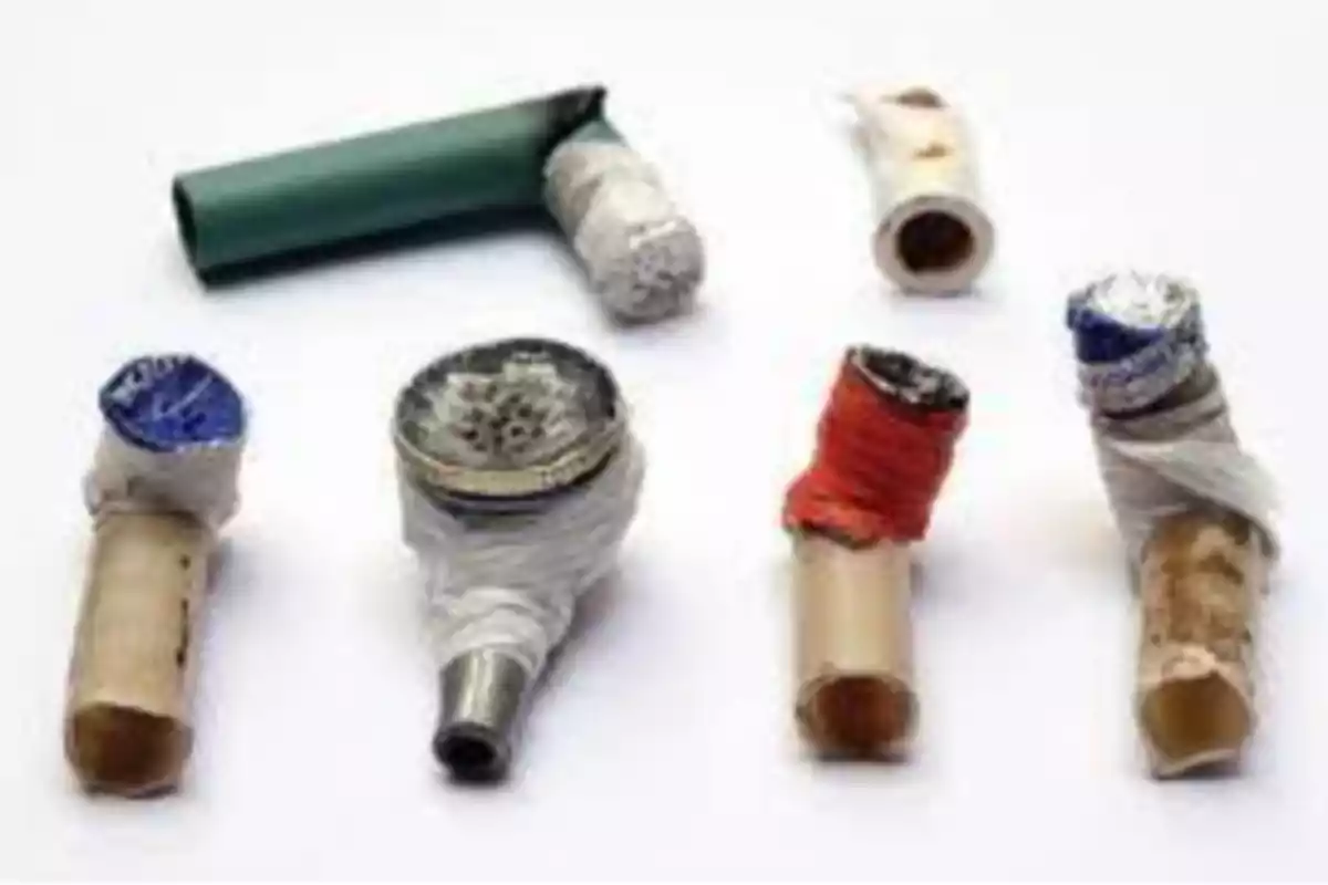 Varios tubos pequeños hechos con materiales caseros y envueltos con cinta, utilizados como pipas improvisadas sobre una superficie blanca Varios tubos pequeños hechos con materiales caseros y envueltos con cinta, utilizados como pipas improvisadas sobre una superficie blanca