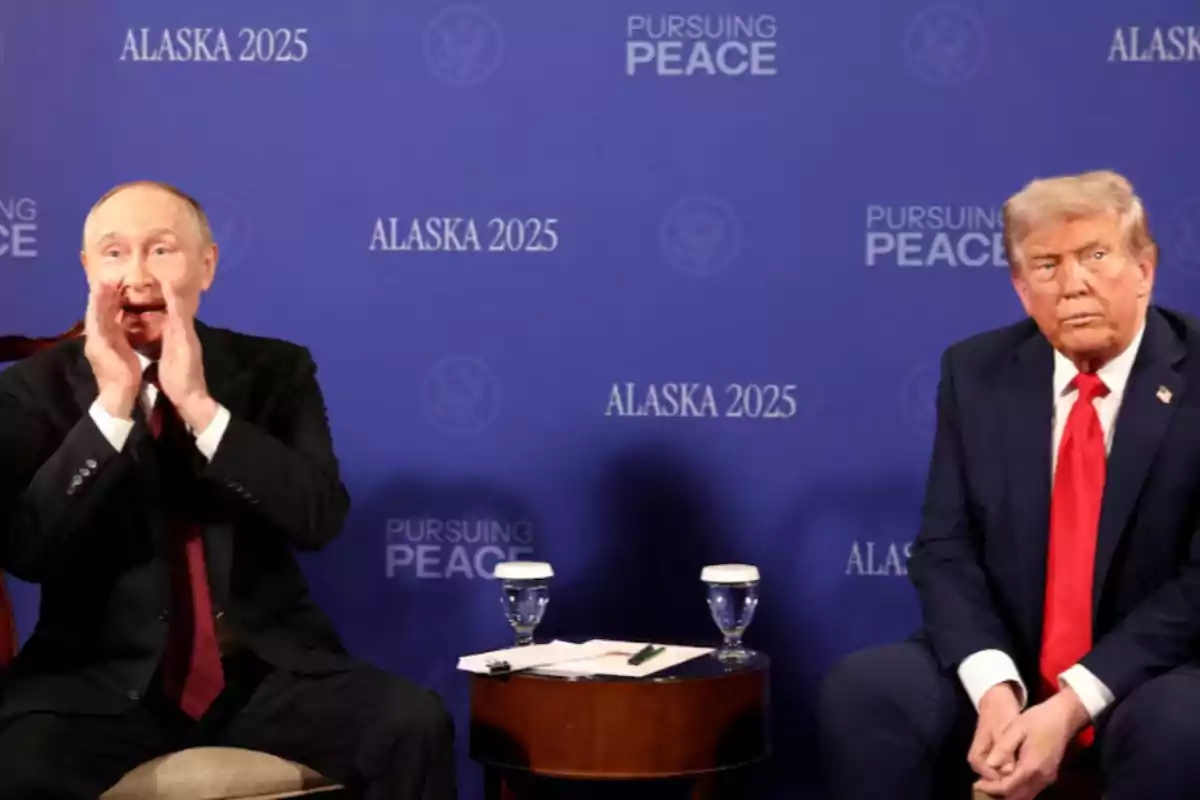 Two men in dark suits sitting in front of a blue background with the words Alaska 2025 and Pursuing Peace, one of them gesturing with his hands near his mouth and the other looking forward with a serious expression. Two men in dark suits sitting in front of a blue background with the words Alaska 2025 and Pursuing Peace, one of them gesturing with his hands near his mouth and the other looking forward with a serious expression.