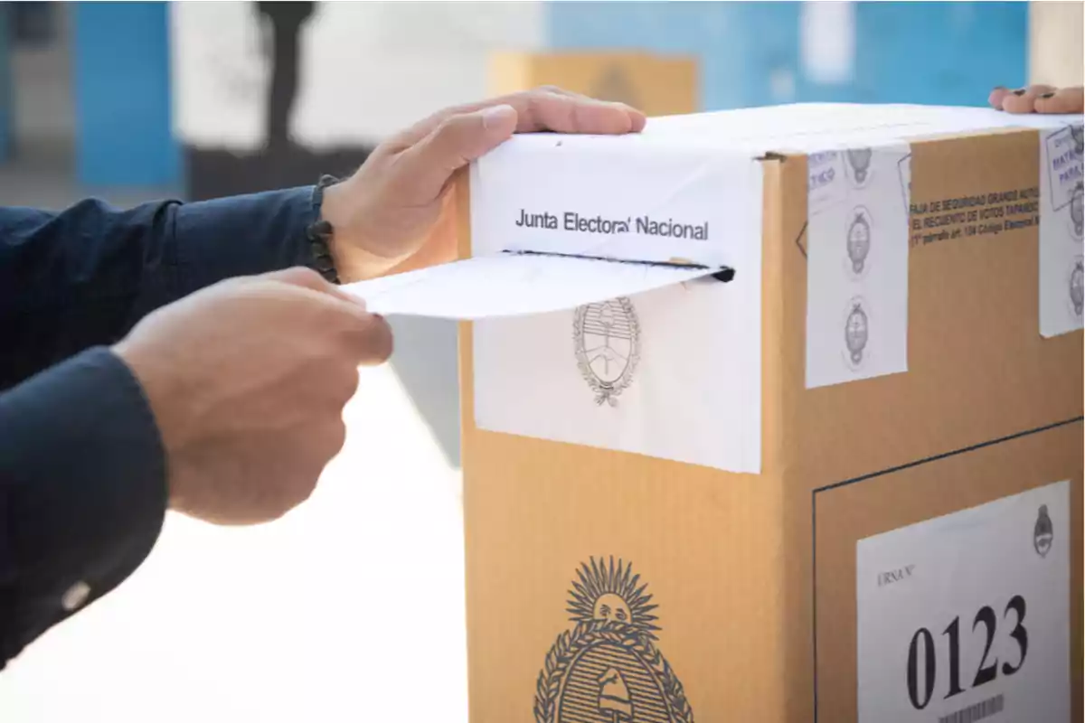 Person inserting an envelope into a cardboard ballot box during a vote in Argentina