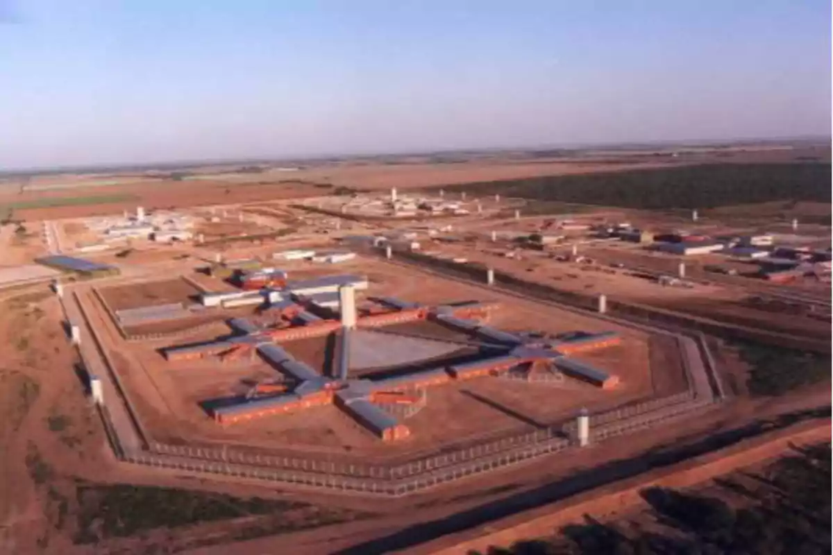 Vista aérea de una prisión de alta seguridad rodeada de muros y torres de vigilancia en una zona desértica Vista aérea de una prisión de alta seguridad rodeada de muros y torres de vigilancia en una zona desértica