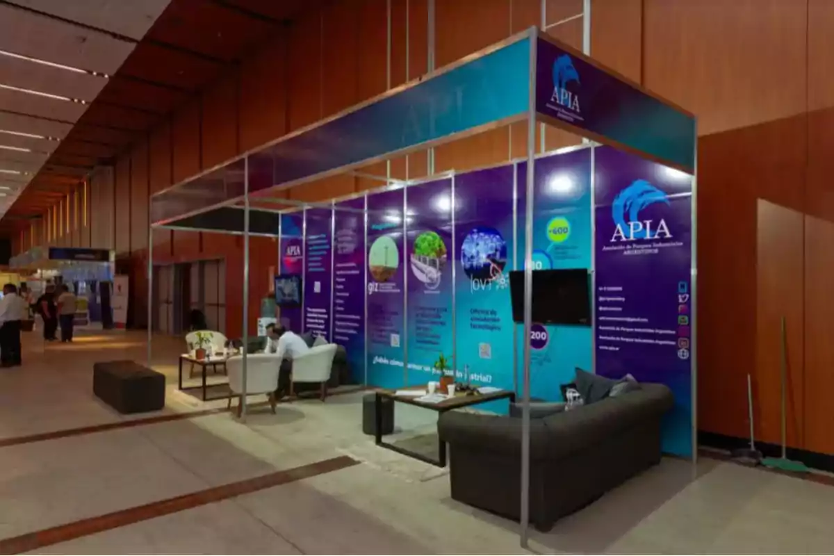 Booth of the Argentine Industrial Parks Association at an exhibition with armchairs, tables, and informational material in an indoor setting.