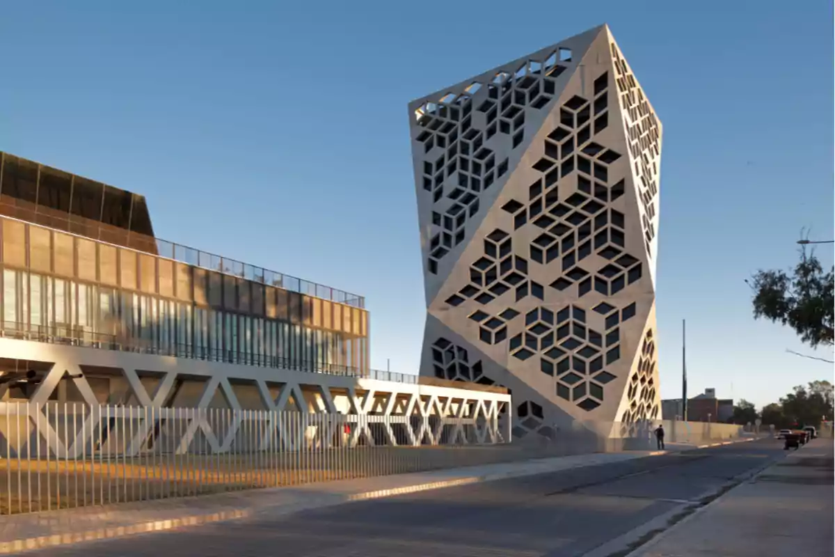 Edificio moderno con fachada geométrica y ventanas en forma de cubos ubicado junto a una calle bajo un cielo despejado
