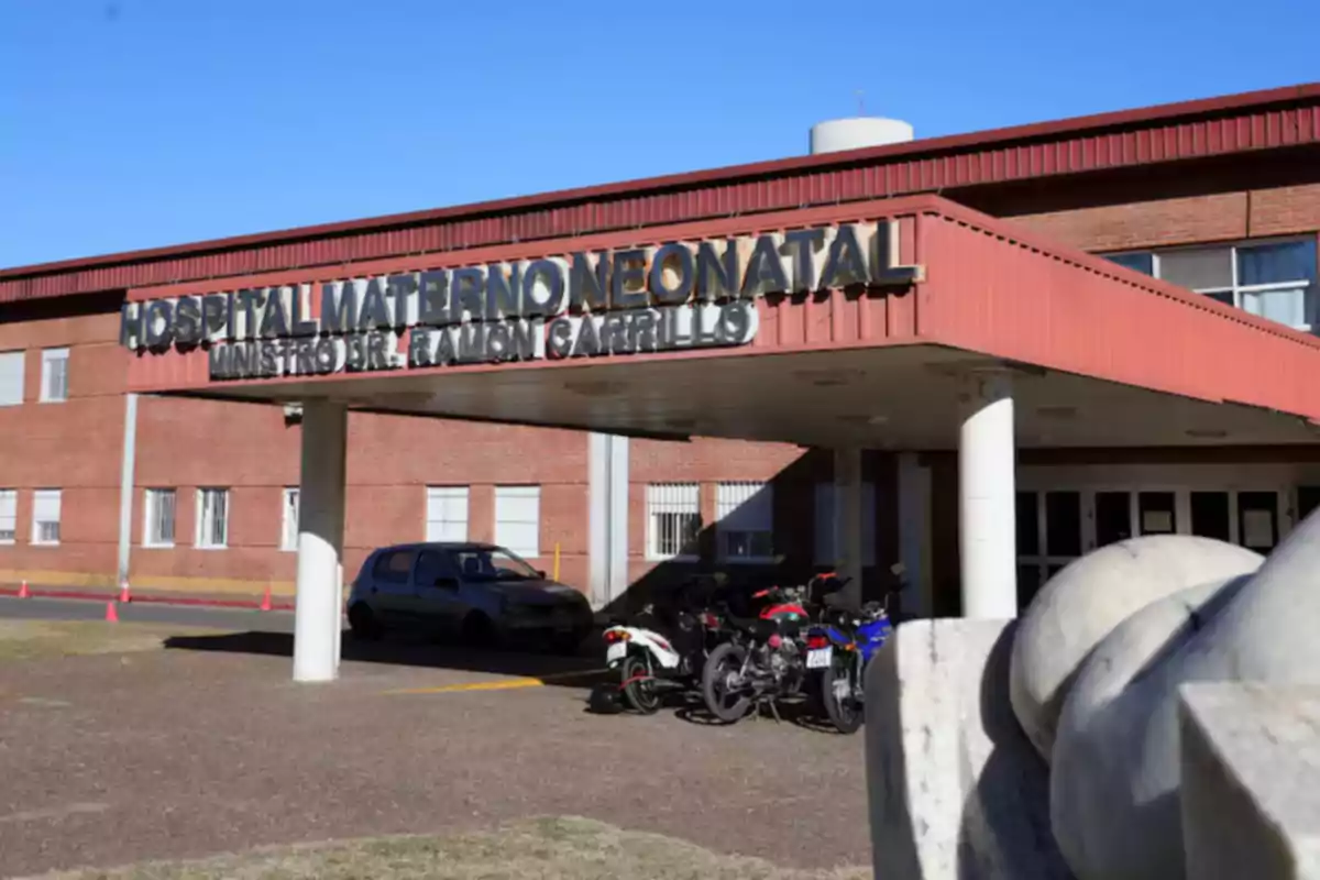 Main entrance of a maternal and neonatal hospital with several motorcycles and a car parked in front of the red brick building Main entrance of a maternal and neonatal hospital with several motorcycles and a car parked in front of the red brick building
