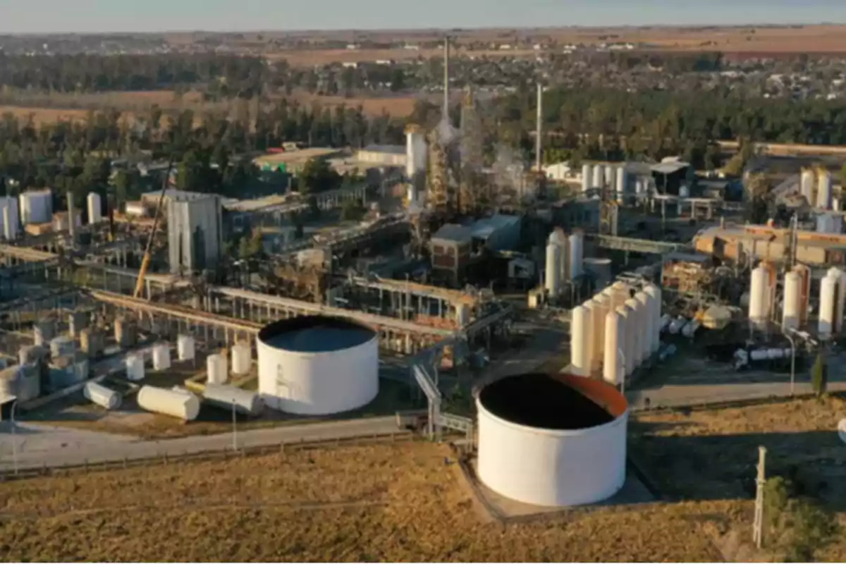 Aerial view of an industrial plant with large storage tanks and several structures surrounded by vegetation and roads Aerial view of an industrial plant with large storage tanks and several structures surrounded by vegetation and roads