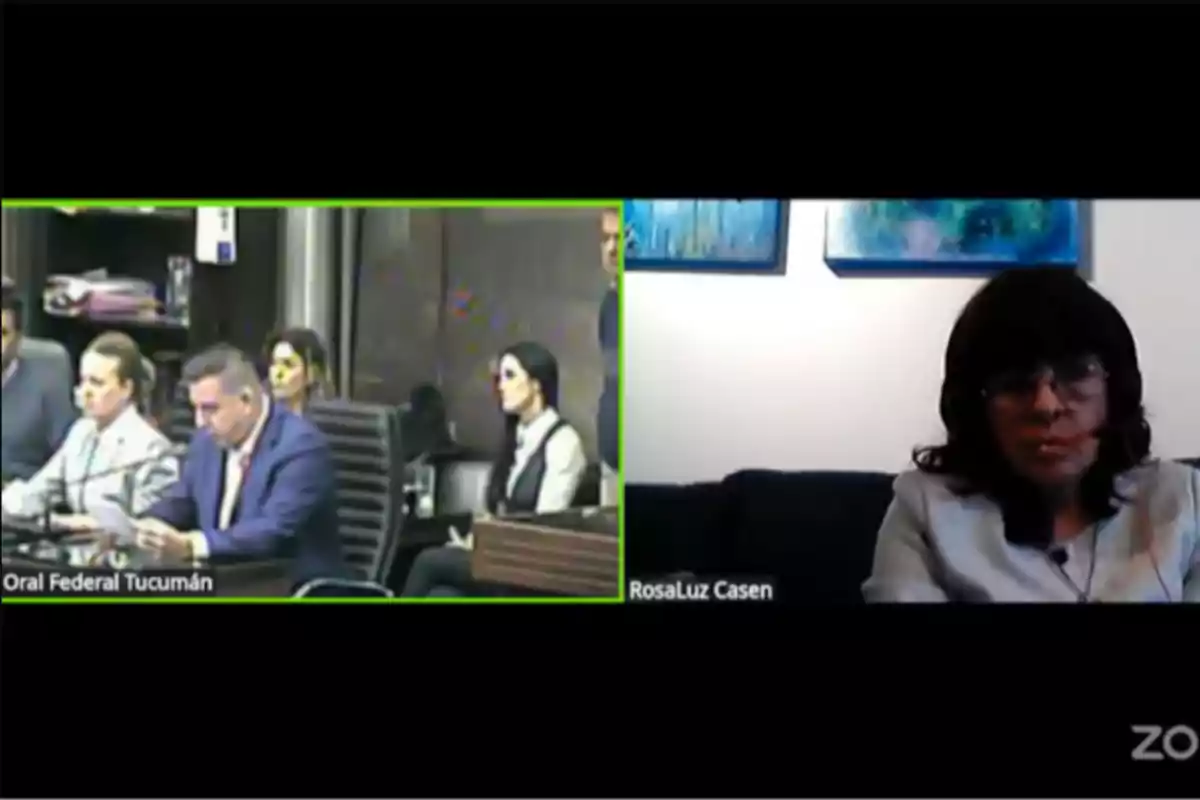 Split video call with two screens: on the left, several people are seen in a courtroom, and on the right, a woman is sitting on a couch in front of a white wall with blue pictures. Split video call with two screens: on the left, several people are seen in a courtroom, and on the right, a woman is sitting on a couch in front of a white wall with blue pictures.