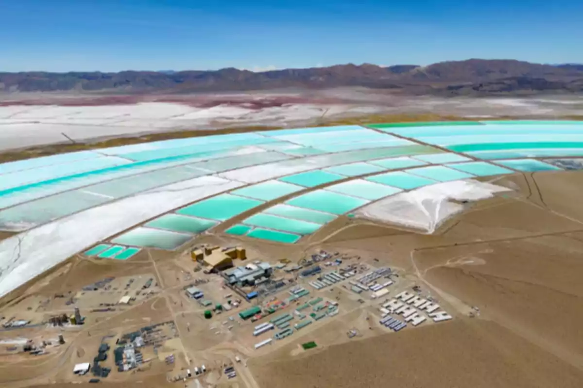 Vista aérea de una planta de extracción de litio con grandes piletas de evaporación de color turquesa en un paisaje desértico rodeado de montañas. Vista aérea de una planta de extracción de litio con grandes piletas de evaporación de color turquesa en un paisaje desértico rodeado de montañas.
