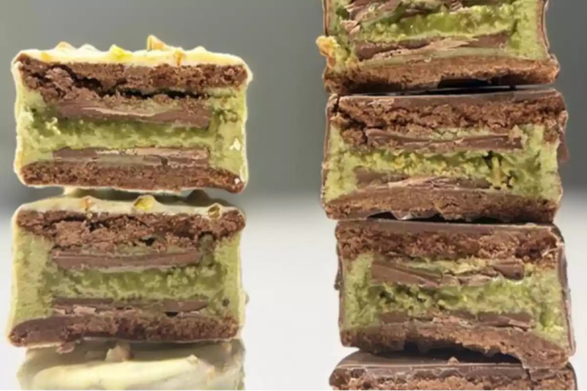 Galletas rellenas de crema verde y capas de chocolate apiladas y partidas a la mitad mostrando su interior Galletas rellenas de crema verde y capas de chocolate apiladas y partidas a la mitad mostrando su interior