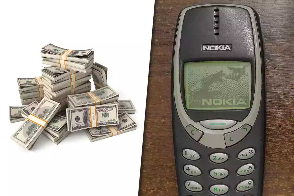 Varios fajos de billetes de cien dólares junto a un teléfono celular antiguo Nokia sobre una mesa de madera