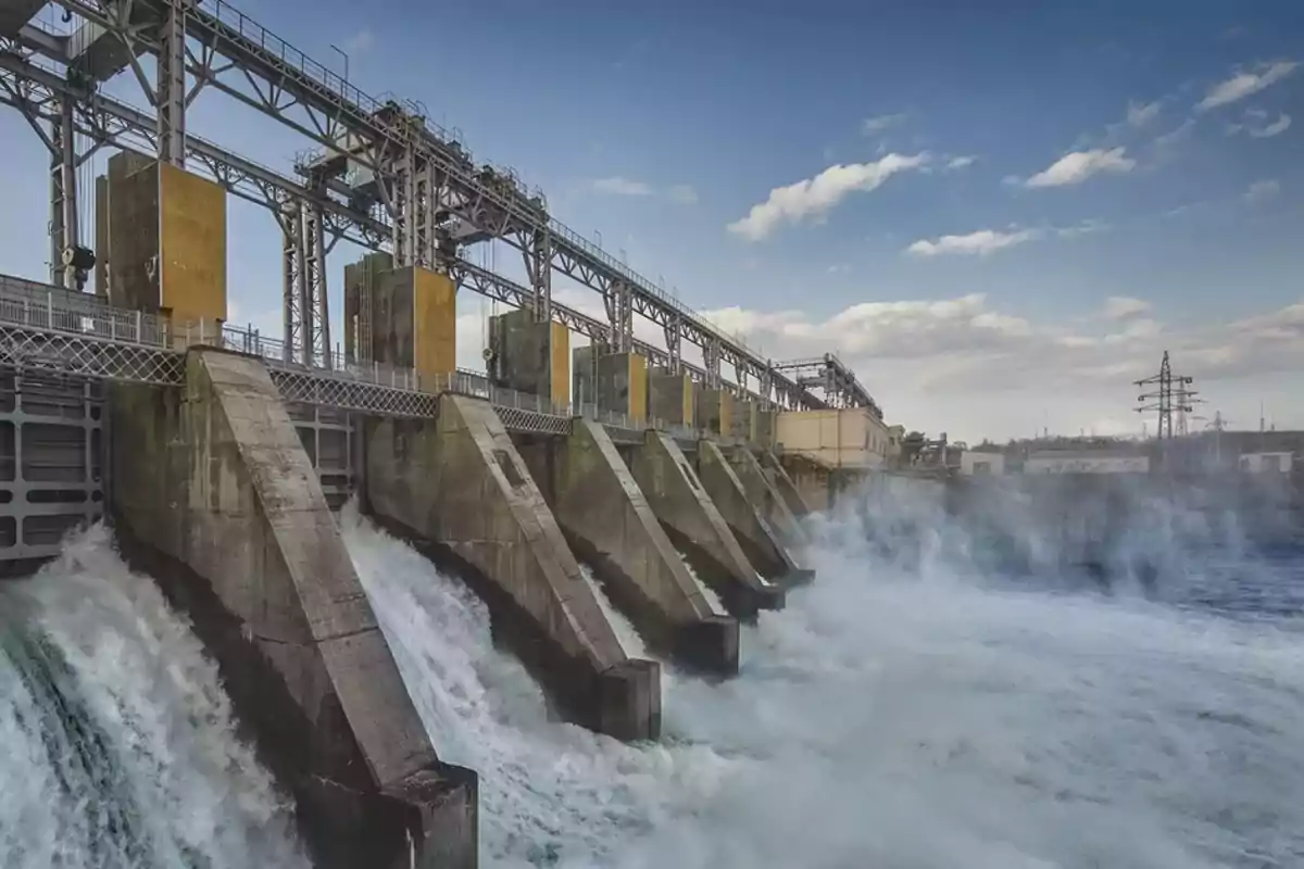 Hydroelectric power plant with water flowing rapidly through the gates under a partly cloudy sky