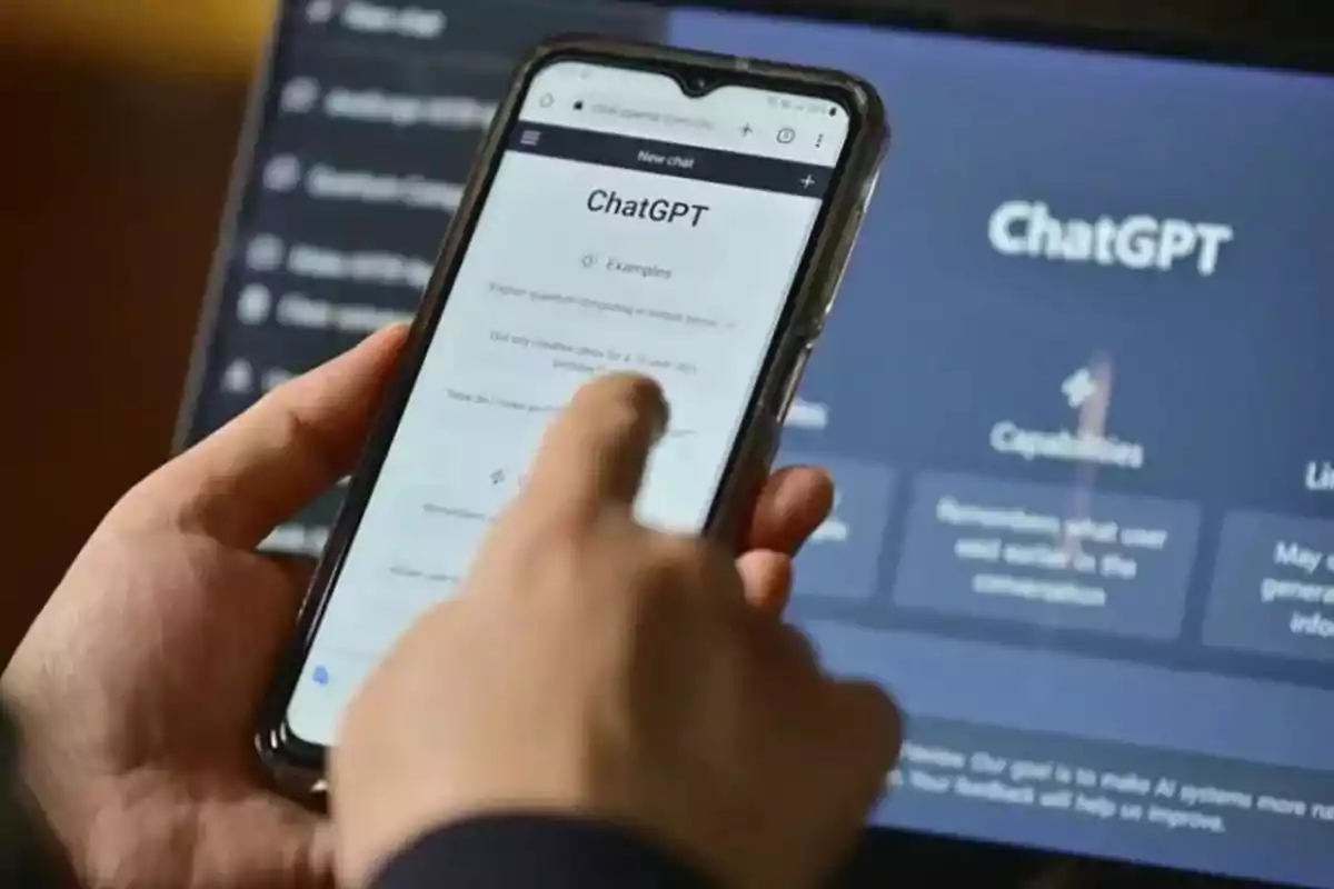 Person using ChatGPT on a mobile phone while a screen with the same application is in the background Person using ChatGPT on a mobile phone while a screen with the same application is in the background