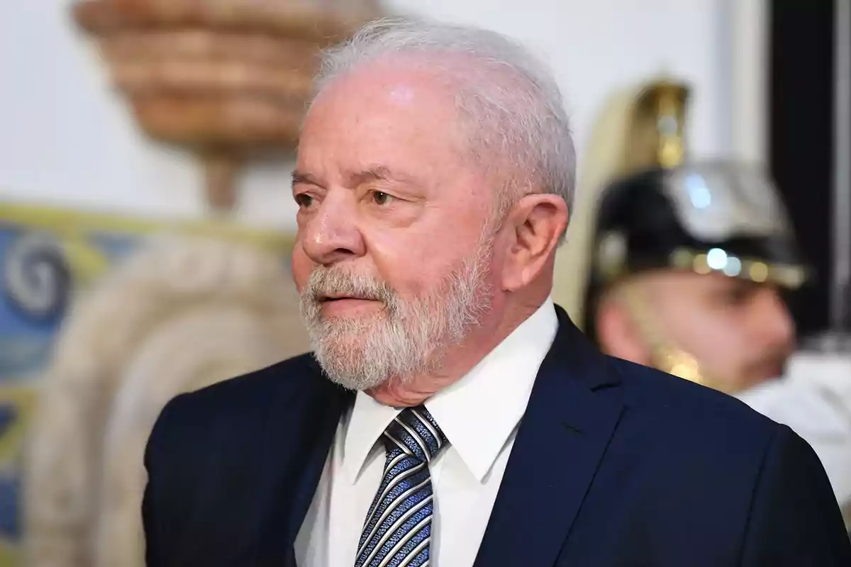 Gray-haired, bearded man in a blue suit and striped tie at a formal event Gray-haired, bearded man in a blue suit and striped tie at a formal event