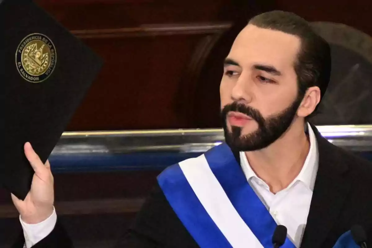Man with a blue and white presidential sash holding a black folder with the coat of arms of El Salvador
