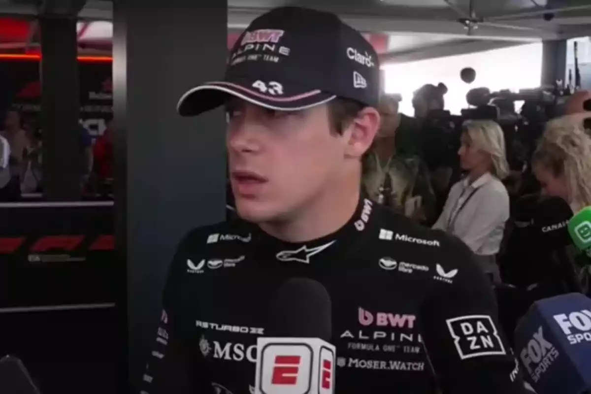 Formula 1 driver wearing an Alpine cap and uniform being interviewed by several media outlets in a press area