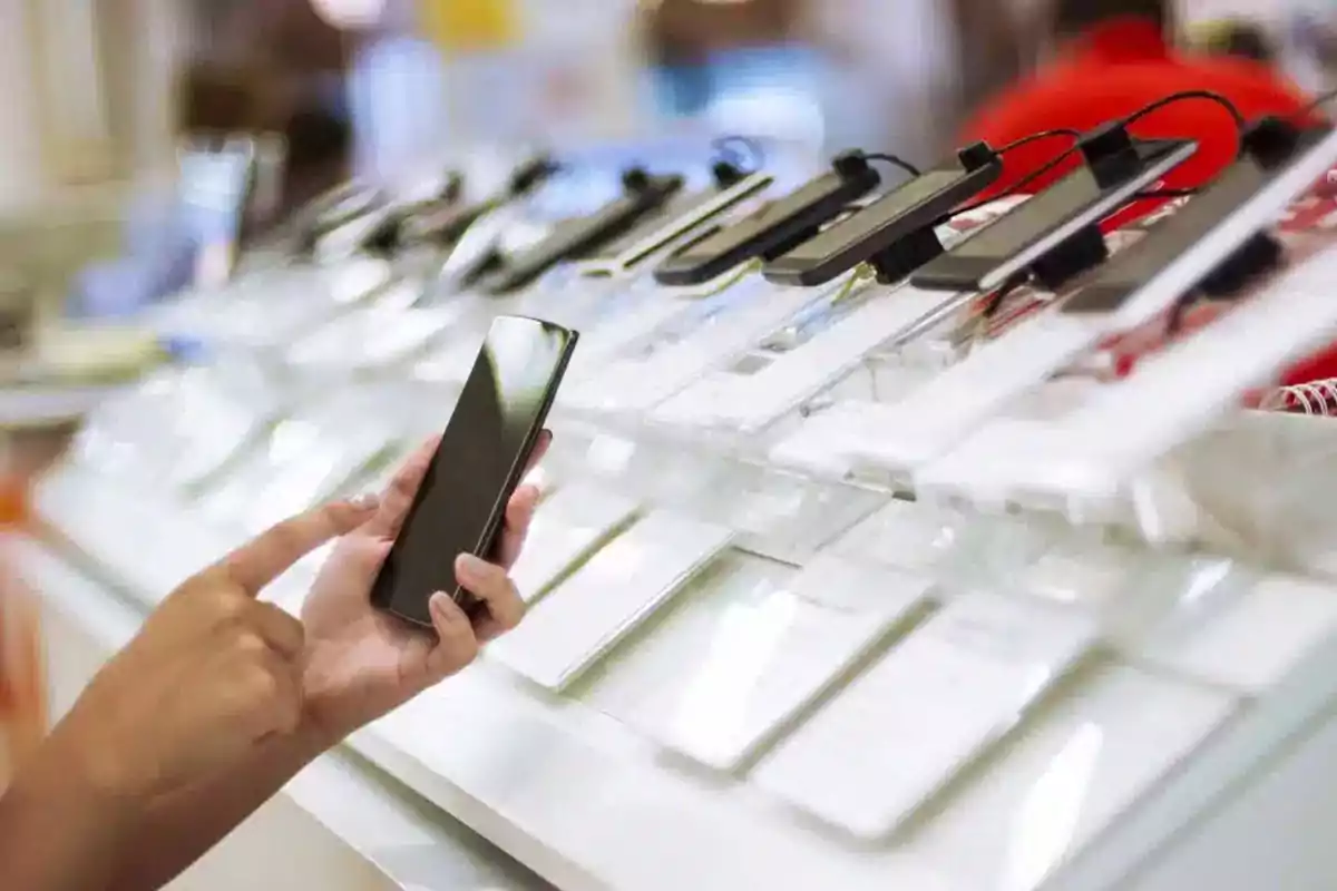 Person testing a mobile phone in a tech store with several devices on display Person testing a mobile phone in a tech store with several devices on display