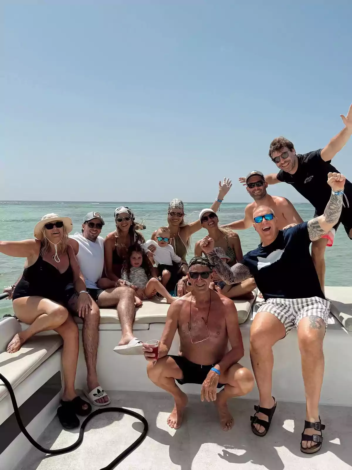 Grupo de personas sonrientes disfrutando de un día soleado en un bote sobre el mar Grupo de personas sonrientes disfrutando de un día soleado en un bote sobre el mar