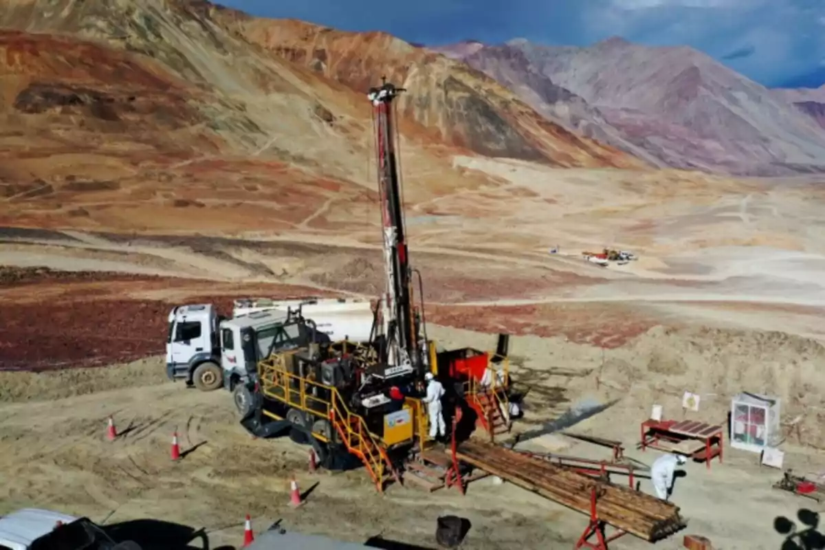 Mining drilling rig operating in an arid mountainous landscape with workers and vehicles around Mining drilling rig operating in an arid mountainous landscape with workers and vehicles around