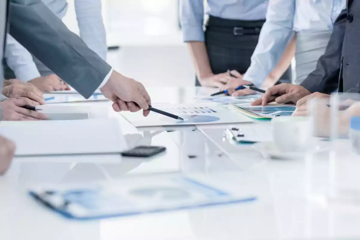 Business people reviewing charts and documents at an office table during a meeting Business people reviewing charts and documents at an office table during a meeting