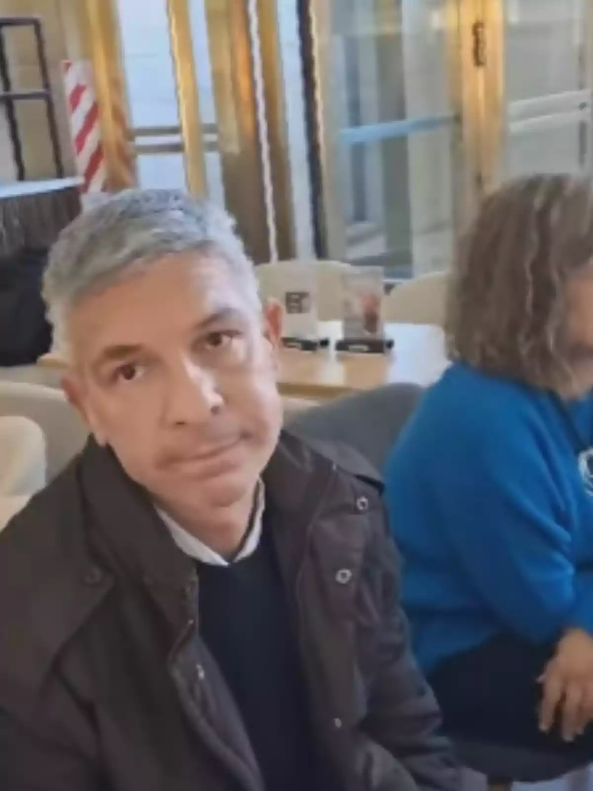 Gray-haired man in a dark jacket sitting in a café next to a woman in a blue sweater Gray-haired man in a dark jacket sitting in a café next to a woman in a blue sweater