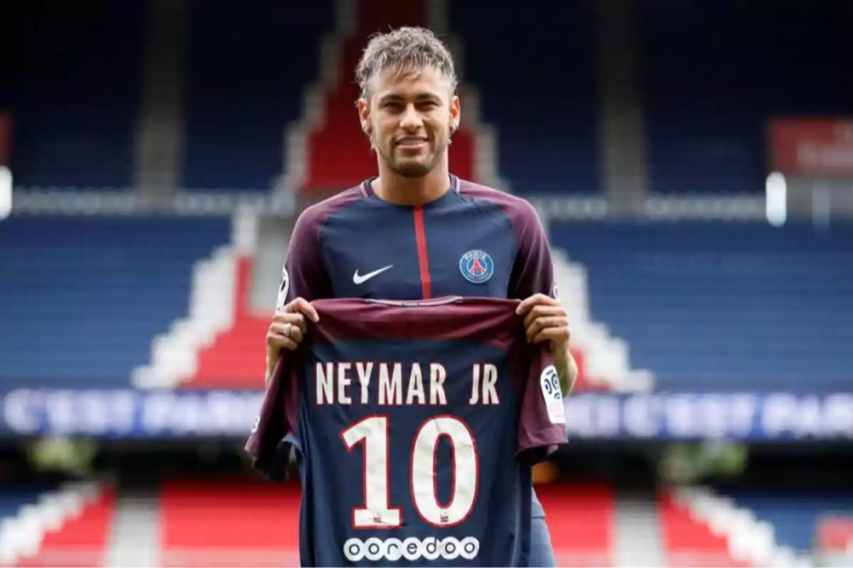 Soccer player in a PSG uniform holding a jersey with the name Neymar Jr and the number 10 in an empty stadium Soccer player in a PSG uniform holding a jersey with the name Neymar Jr and the number 10 in an empty stadium