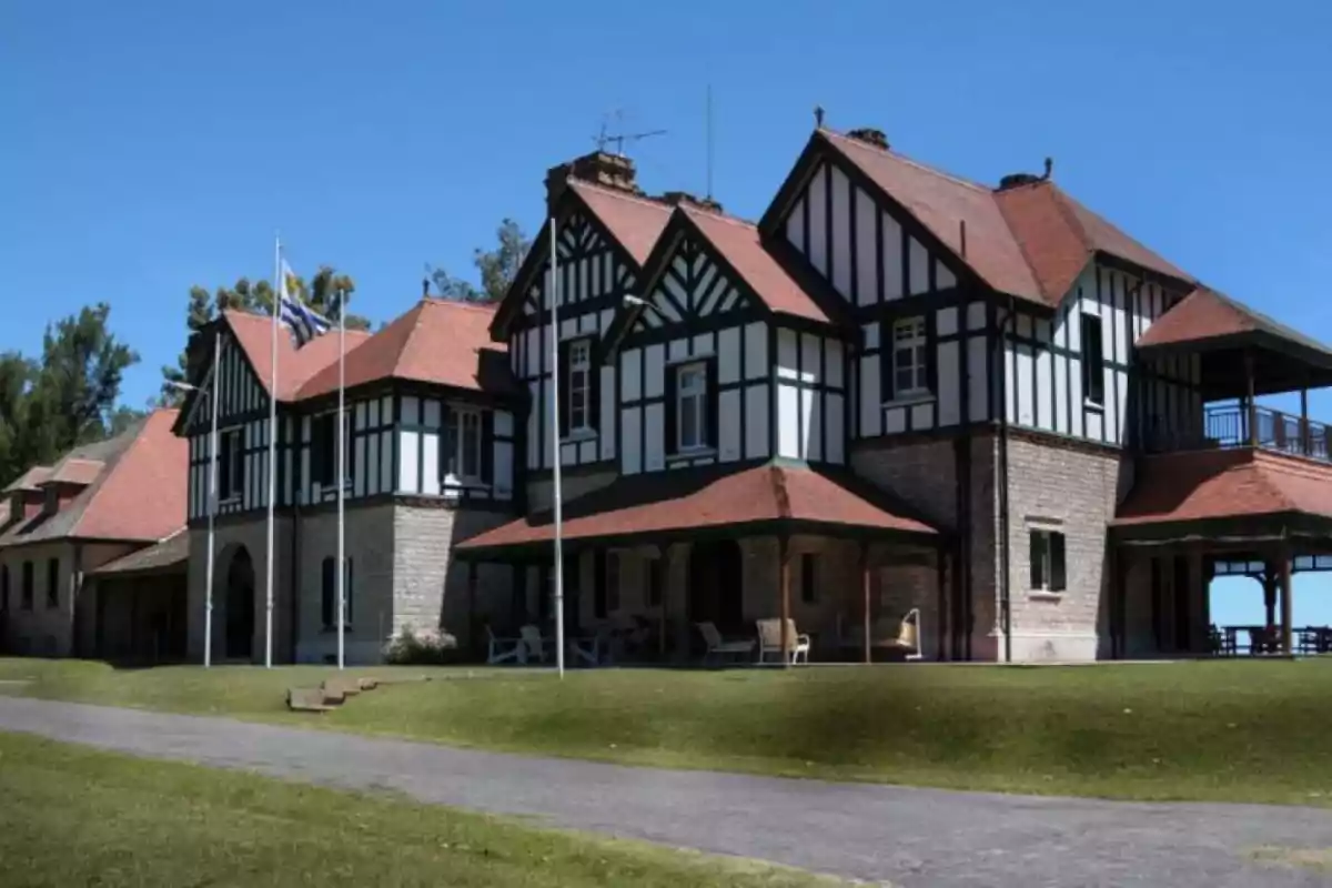 Large English-style building with a gabled roof and stone and wood walls, surrounded by lawn and clear sky Large English-style building with a gabled roof and stone and wood walls, surrounded by lawn and clear sky