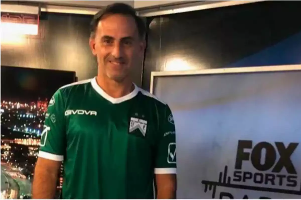 Hombre con camiseta verde de fútbol posando en un estudio de televisión con el logo de Fox Sports al fondo