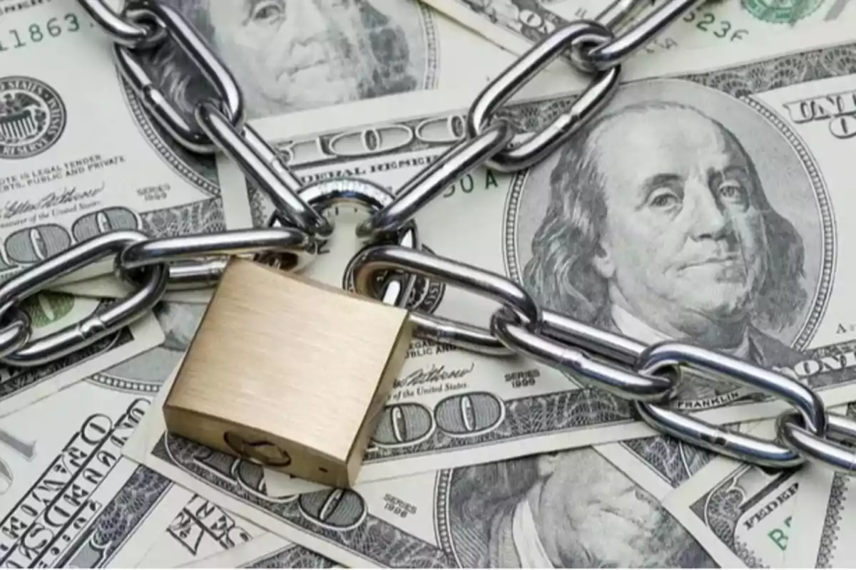 Hundred-dollar bills covered with a metal chain and a padlock Hundred-dollar bills covered with a metal chain and a padlock