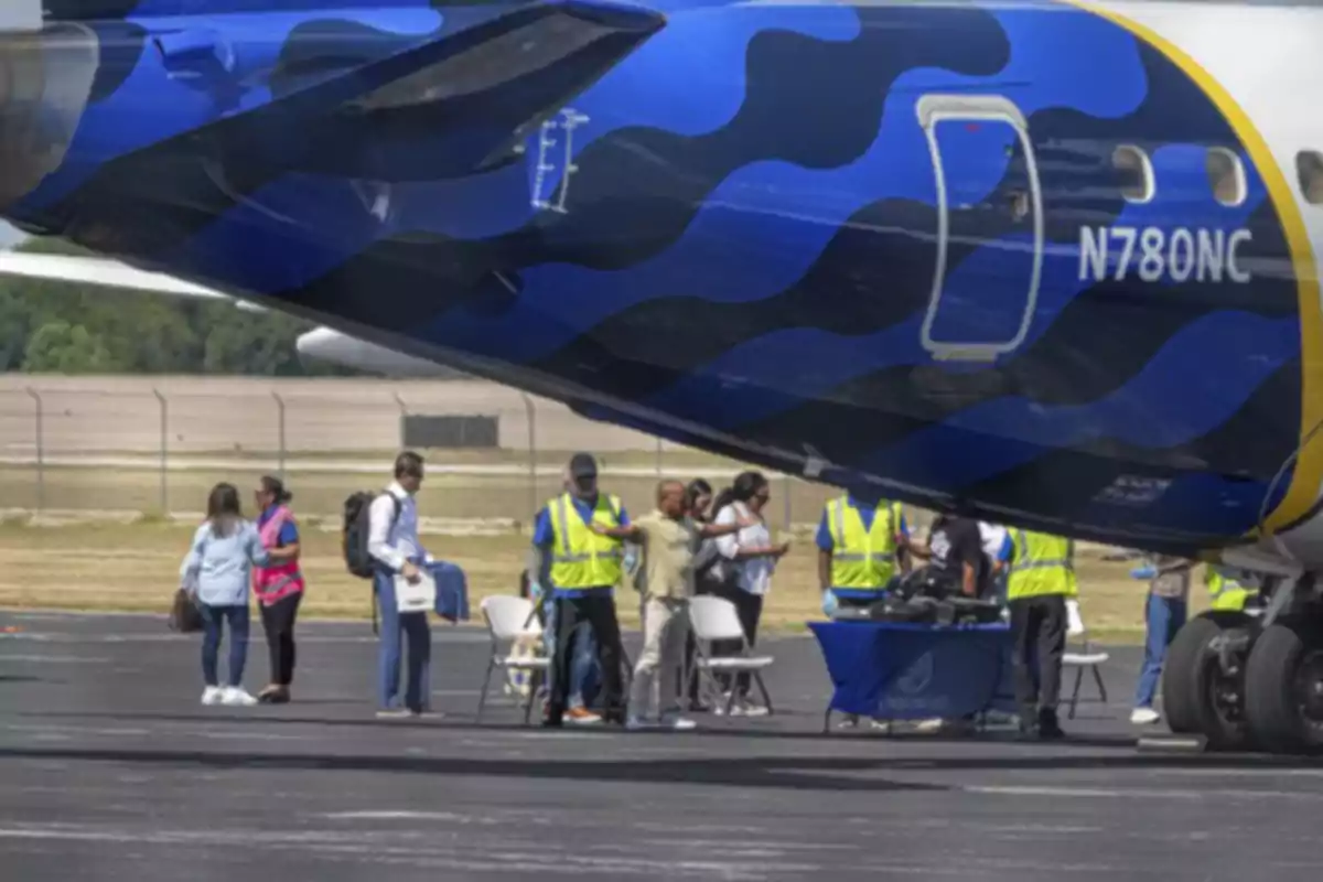 People being screened by security personnel next to an airplane on a runway