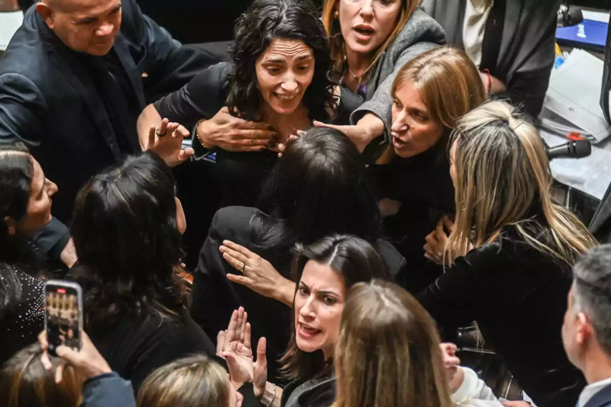 Several people argue heatedly and push each other in a confined space while others try to separate them.