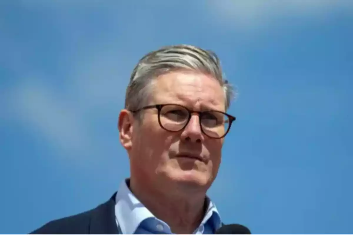Hombre de cabello canoso y gafas de pie al aire libre con el cielo azul de fondo