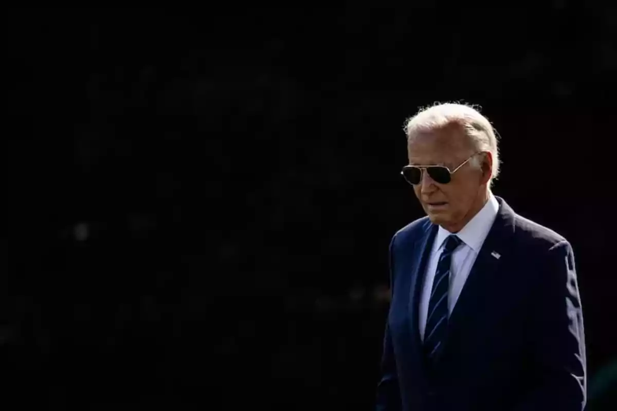 Hombre mayor con gafas de sol y traje azul caminando sobre un fondo oscuro Hombre mayor con gafas de sol y traje azul caminando sobre un fondo oscuro