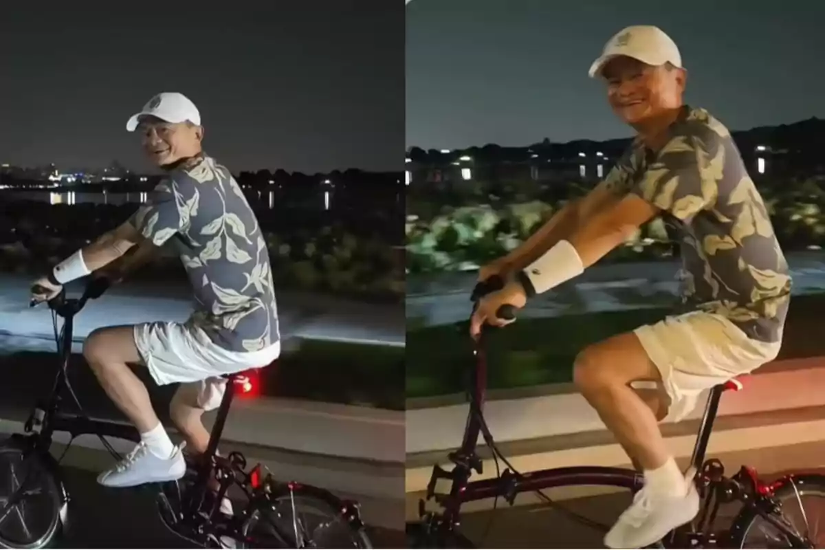 Hombre sonriente con gorra blanca y ropa casual montando una bicicleta por la noche junto a un lago iluminado Hombre sonriente con gorra blanca y ropa casual montando una bicicleta por la noche junto a un lago iluminado
