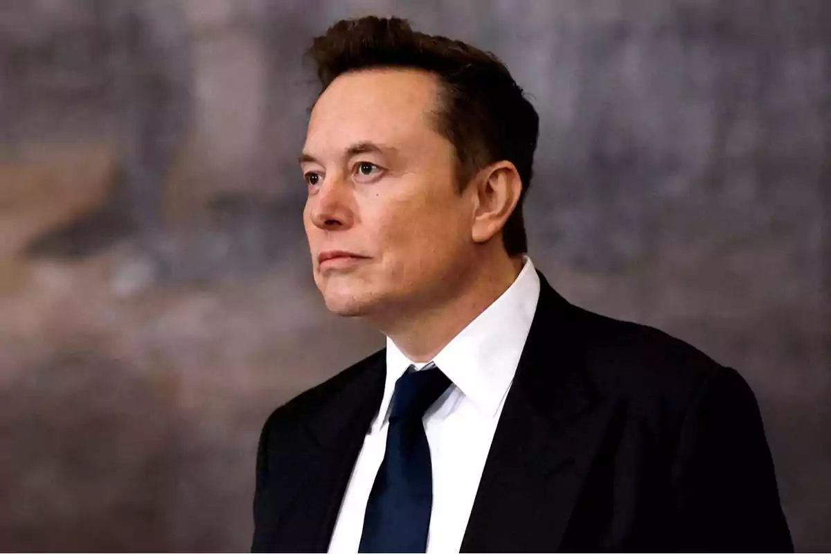 Hombre de cabello corto y oscuro vistiendo traje negro con camisa blanca y corbata azul mirando hacia la izquierda con expresión seria Hombre de cabello corto y oscuro vistiendo traje negro con camisa blanca y corbata azul mirando hacia la izquierda con expresión seria