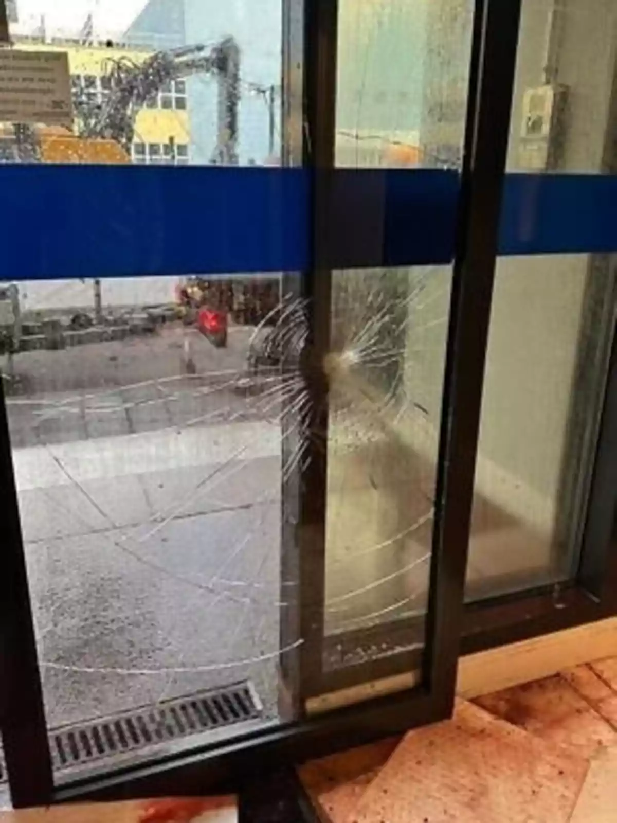 Puerta de vidrio corrediza con un gran impacto y grietas en el cristal en un día lluvioso Puerta de vidrio corrediza con un gran impacto y grietas en el cristal en un día lluvioso