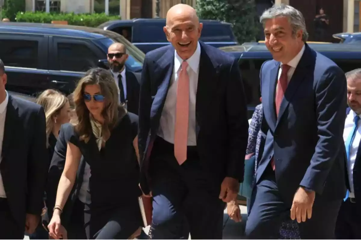 Group of people dressed in suits walking and smiling outdoors in an urban setting with black cars in the background. Group of people dressed in suits walking and smiling outdoors in an urban setting with black cars in the background.