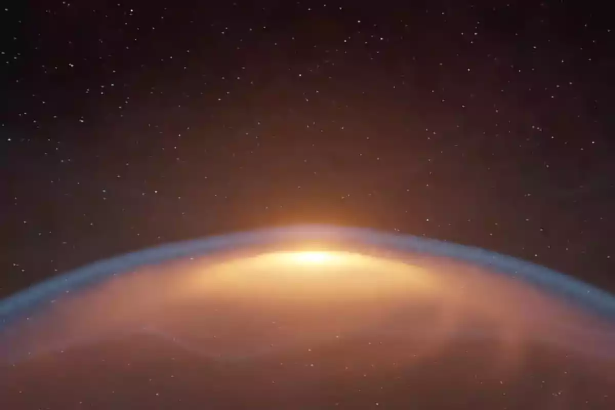Amanecer visto desde el espacio con un resplandor anaranjado en el horizonte y un cielo estrellado