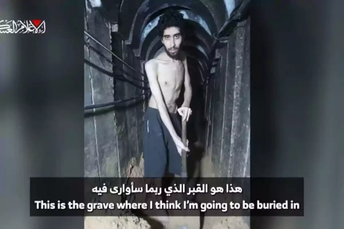 Un hombre delgado y sin camisa sostiene una pala dentro de un túnel oscuro y angosto, con un texto en árabe e inglés en la parte inferior que dice que cree que ese es el lugar donde será enterrado. Un hombre delgado y sin camisa sostiene una pala dentro de un túnel oscuro y angosto, con un texto en árabe e inglés en la parte inferior que dice que cree que ese es el lugar donde será enterrado.