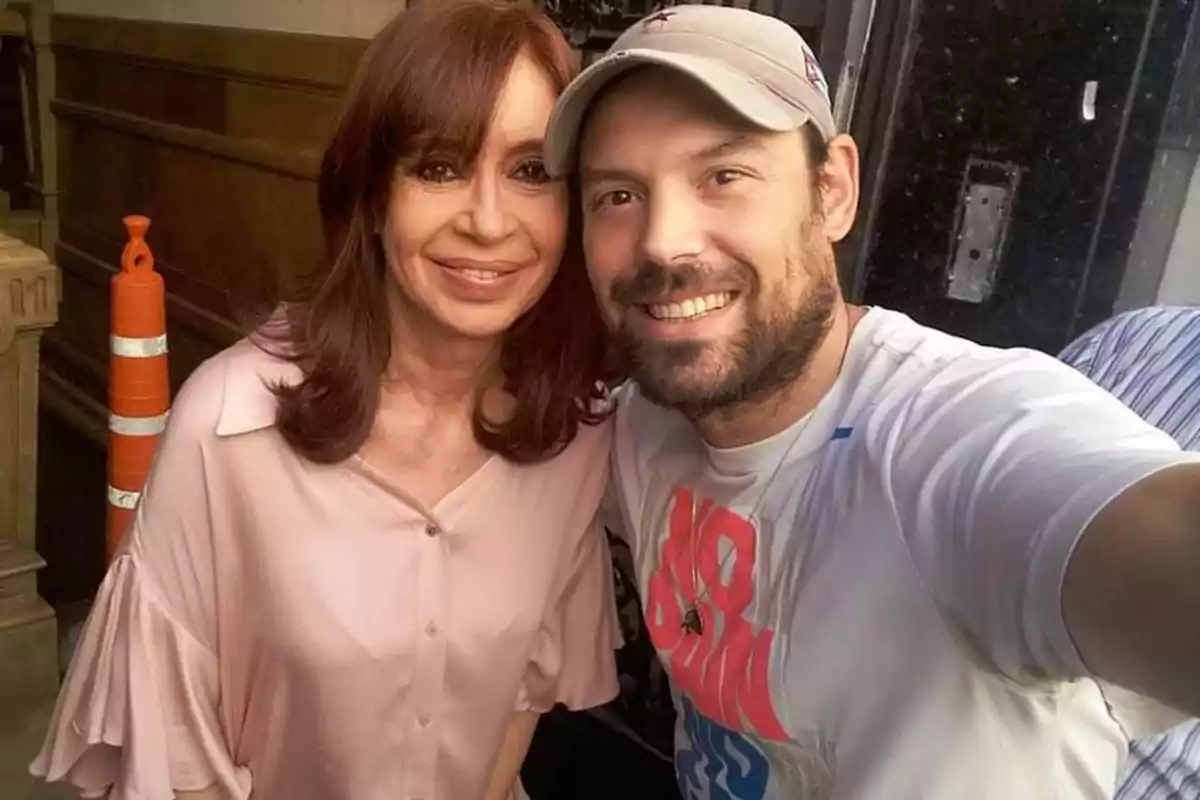 Two people smile as they pose together for a selfie in an urban setting, with an orange traffic cone in the background. Two people smile as they pose together for a selfie in an urban setting, with an orange traffic cone in the background.