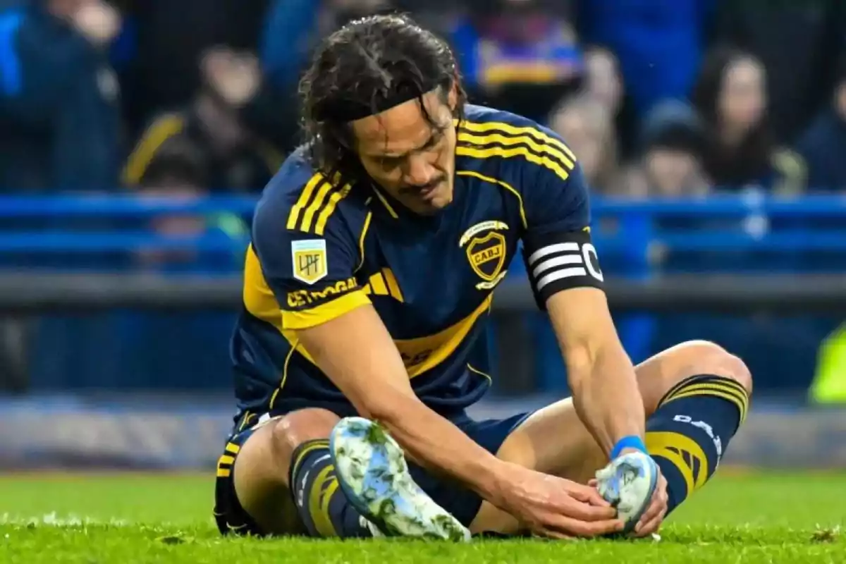 Soccer player sitting on the grass with a pained expression while holding his foot during a match Soccer player sitting on the grass with a pained expression while holding his foot during a match