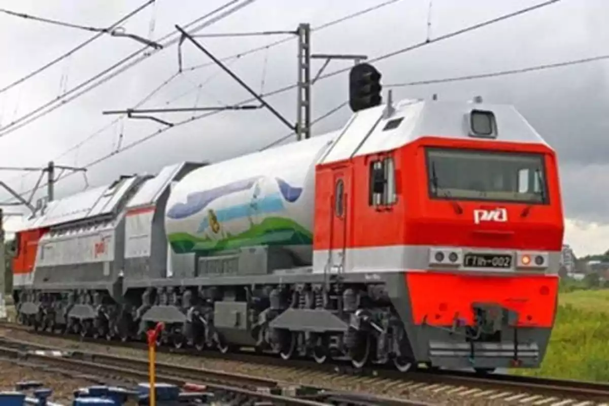 Modern freight train with a red and silver locomotive running on railroad tracks in a rural setting under a cloudy sky Modern freight train with a red and silver locomotive running on railroad tracks in a rural setting under a cloudy sky